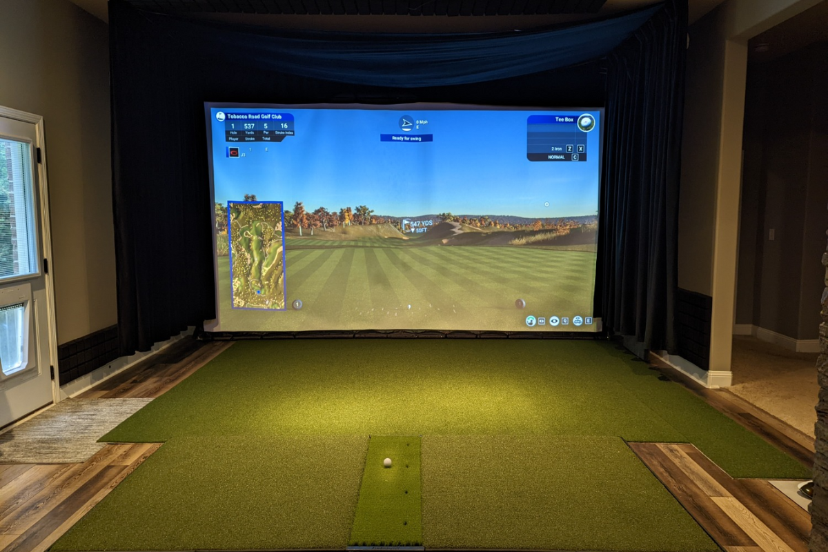Basement golf simulator with a built-in impact screen, side curtains and full turf floor